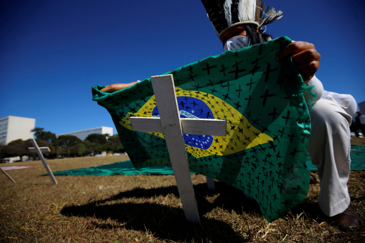 An activist puts a Brazilian flag painted with crosses on a cross