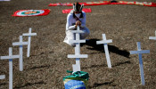 An activist kneels next to crosses