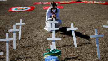 An activist kneels next to crosses