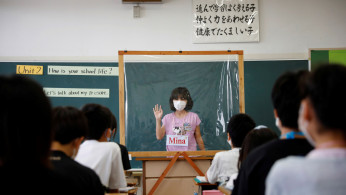 A student wearing a protective face mask makes a presentation 