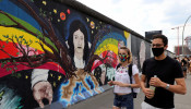Tourists from France wear face masks as they walk past the East Side Gallery,