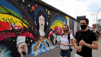 Tourists from France wear face masks as they walk past the East Side Gallery,