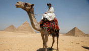 A man with a camel is seen in front of the Great Pyramid of Giza