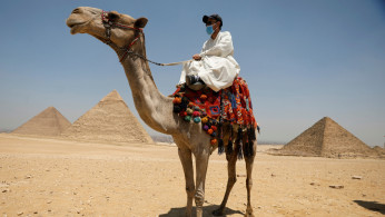 A man with a camel is seen in front of the Great Pyramid of Giza