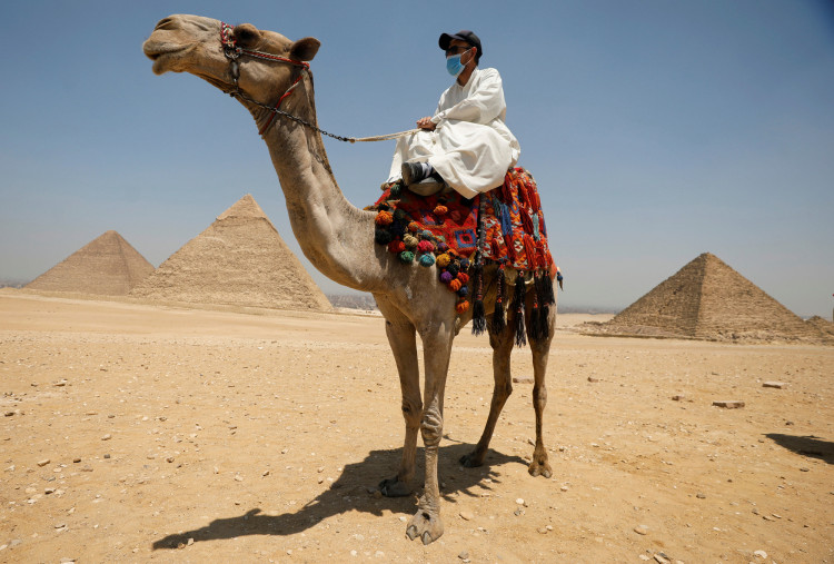 A man with a camel is seen in front of the Great Pyramid of Giza