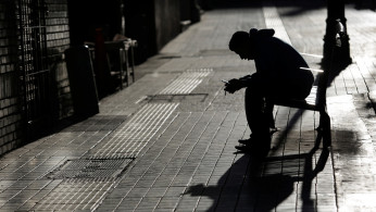 A man checks his phone while sitting on a bench