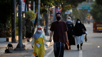 Indonesian Muslims walking to Eid al-Adha prayers wearing face masks