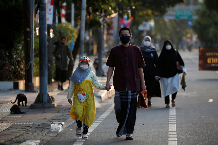 Indonesian Muslims walking to Eid al-Adha prayers wearing face masks