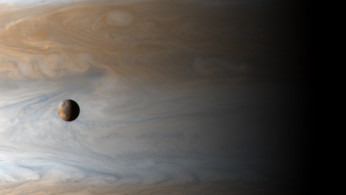 The Galilean satellite Io floats above the cloudtops of Jupiter