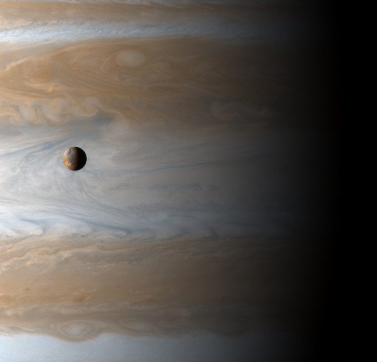 The Galilean satellite Io floats above the cloudtops of Jupiter