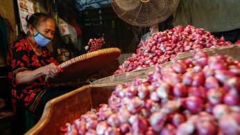 A worker wearing a protective face mask sorts onion