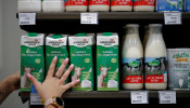 An employee prepares goat's milk cartons as she restocks a sales display