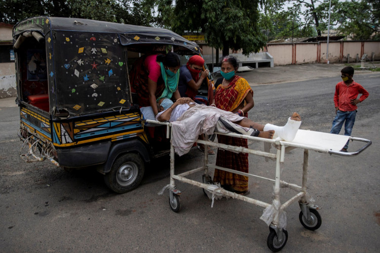 A patient is moved by relatives onto an auto-rickshaw