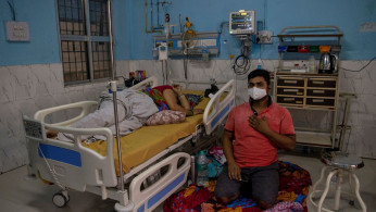 A COVID-19 patient lies on a hospital bed