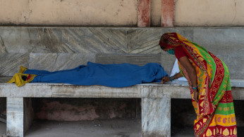 A woman places incense sticks next to the body 