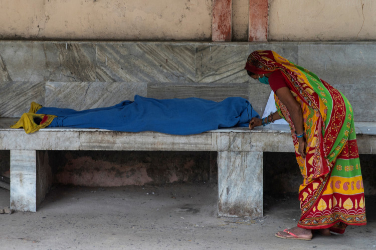 A woman places incense sticks next to the body 