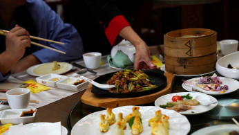 A waitress serves dishes for customers at the Quanjude Peking roast duck restaurant