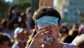 A man smokes a cigarette with his eyes covered by a face mask as he takes part in a protest against the use of protective masks during the coronavirus disease pandemic