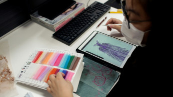 A designer looks at fabric swatches at Suzhou Jusere Wedding & Evening Dress