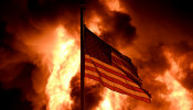 Flames engulf the Community Corrections Division building as an American flag flutters