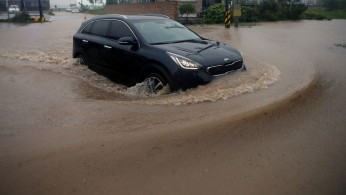 A SUV vehicle drives through a submerged road 