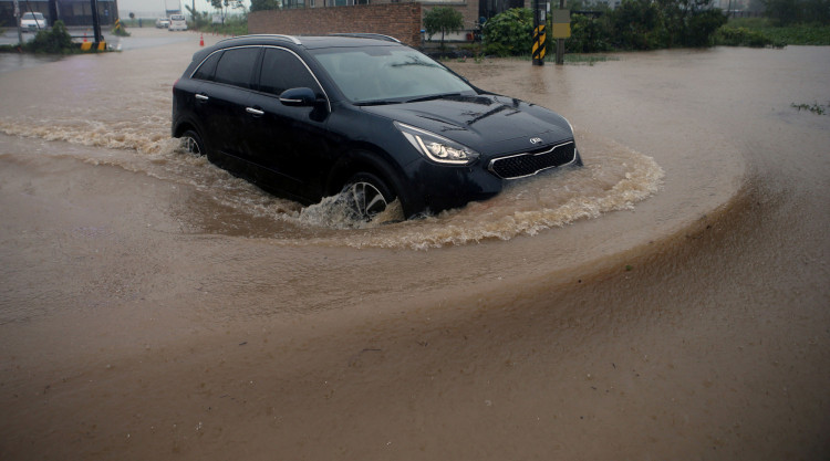 A SUV vehicle drives through a submerged road 