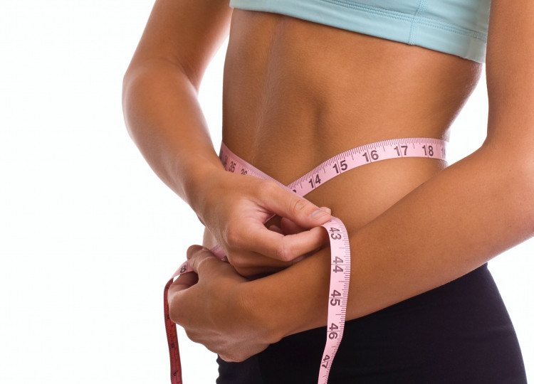 Woman measuring stomach with measuring tape.