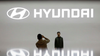 FILE PHOTO: Visitors take photographs in front of the logo of Hyundai Motor during the 2019 Seoul Motor Show in Goyang