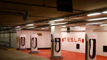 A Tesla electric charging point stands unused in a car park