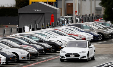 FILE PHOTO: A Tesla Model S electric vehicle drives along a row of occupied superchargers at Tesla's primary vehicle factory in Fremont, California
