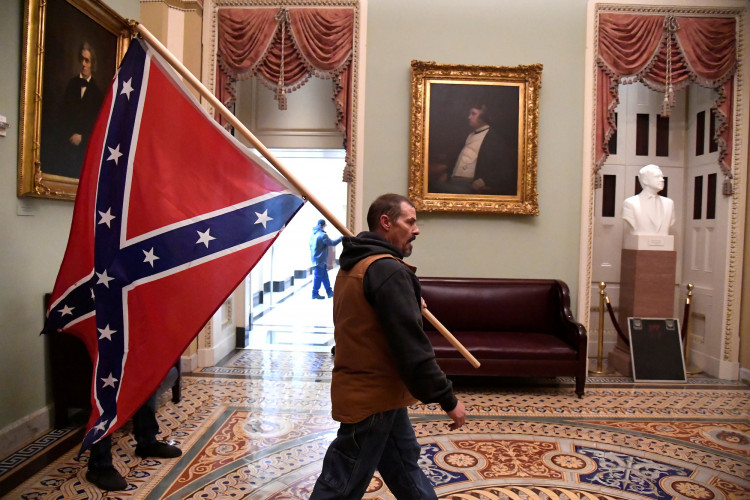 A supporter of President Donald Trump carries a Conferderate battle on the second floor of the U.S. Capitol near the entrance to the Senate