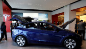 Visitors wearing face masks check a China-made Tesla Model Y sport utility vehicle (SUV) at the electric vehicle maker's showroom in Beijing