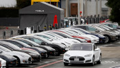 FILE PHOTO: A Tesla Model S electric vehicle drives along a row of occupied Superchargers