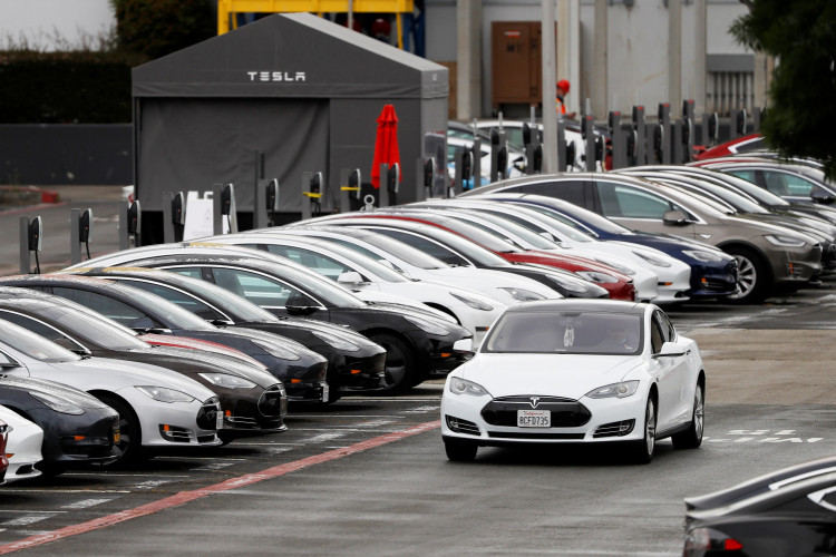 FILE PHOTO: A Tesla Model S electric vehicle drives along a row of occupied Superchargers