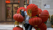 A worker wearing a face mask carries red lanterns, ahead of the Chinese Lunar New Year