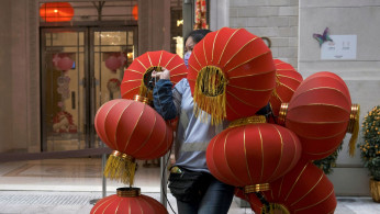 A worker wearing a face mask carries red lanterns, ahead of the Chinese Lunar New Year