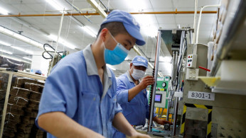 Employees wearing masks work at a factory of the component maker SMC.