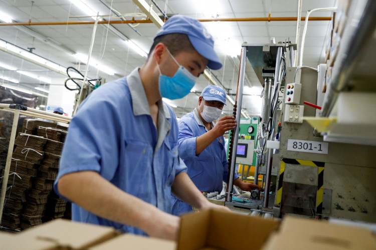 Employees wearing masks work at a factory of the component maker SMC.