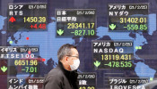 A man walks past a stock quotation board at a brokerage in Tokyo, Japan.
