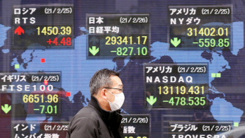 A man walks past a stock quotation board at a brokerage in Tokyo, Japan.