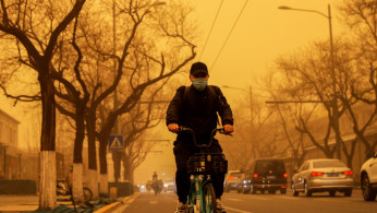 A person cycles down a road during morning rush hour as Beijing, China, is hit by a sandstorm, March 15, 2021.