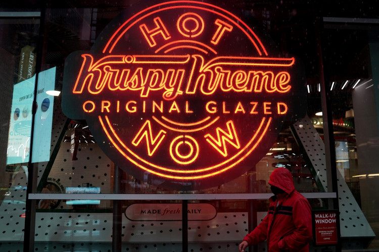 FILE PHOTO: A man walks past a Krispy Kreme "Hot Now" neon sign in Times Square in the Manhattan borough of New York City, New York, U.S., October 16, 2020. 