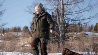 Russian President Vladimir Putin walks through snow during a holiday in the Siberian taiga.