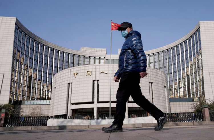 A man wearing a mask walks past the headquarters of the People's Bank of China.