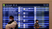  A visitor and an airline company staff member wearing protective face masks are seen at the arrival gate of the international flight terminal at Tokyo International Airport