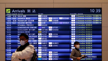  A visitor and an airline company staff member wearing protective face masks are seen at the arrival gate of the international flight terminal at Tokyo International Airport