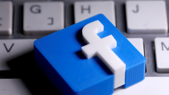 A 3D-printed Facebook logo is seen placed on a keyboard.