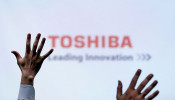 Reporters raise their hands during a Toshiba news conference in Tokyo, Japan.