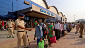 A police officer maintains order as people wearing protective masks wait in line to enter the Lokmanya Tilak Terminus railway station
