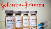 Vials with a sticker reading, 'COVID-19' are seen in front of a displayed Johnson & Johnson logo.